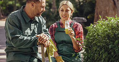Sonnenschutz: Zwei Personen, die im Park eine Trinkpause bei der Gartenarbeit machen und in der Sonne sind Sonnenschutz: Zwei Personen, die im Park eine Trinkpause bei der Gartenarbeit machen und in der Sonne sind