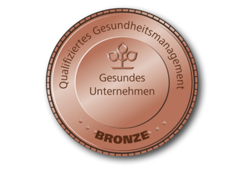 Bronzefarbendes, rundes Siegel auf dem „Gesundes Unternehmen, Qualifiziertes Gesundheitsmanagement“ und „Bronze“ steht.