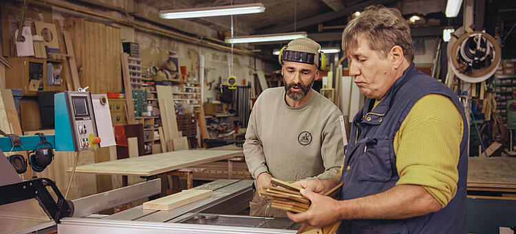 Online-Seminar „Personaleinsatz bei anderen Arbeitgebern“: Zwei Männer besprechen sich in einer Werkstatt. Online-Seminar „Personaleinsatz bei anderen Arbeitgebern“: Zwei Männer besprechen sich in einer Werkstatt.