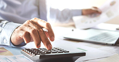 SV-Beiträge 2026: Mann am Schreibtisch tippt auf einem Taschenrechner SV-Beiträge 2026: Mann am Schreibtisch tippt auf einem Taschenrechner