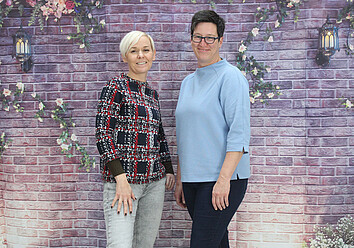 Geschäftsführerinnen des St. Nikolausstifts Zwei Frauen vor Mauer mit Blumen