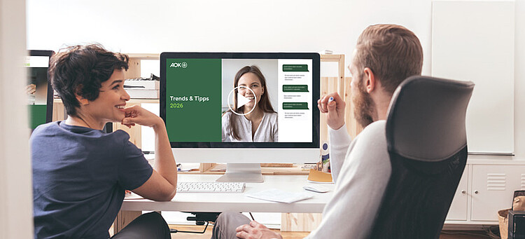 Teilnehmende eines Trends & Tipps Online-Seminars sitzen an einem Tisch und schauen sich die Präsentation an.