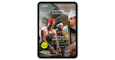 gesundes unternehmen Ausgabe 2-2026: Drei Personen arbeiten zusammen in einer Küche