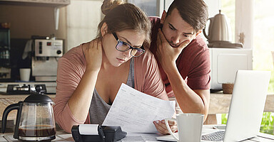 Ein junges Paar schaut sich eine Gehaltsabrechnung an.