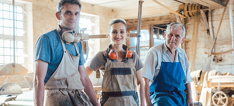 Online-Seminar „GenZ und Babyboomer“: Ein junger Mann, eine junge Frau und ein älterer Mann im Handwerksbetrieb