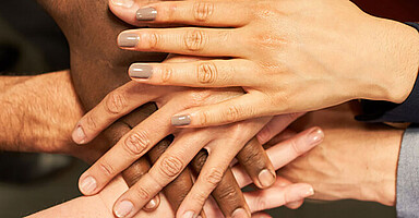 Mehrere Hände von Männer und Frauen liegen gemeinschaftlich übereinander