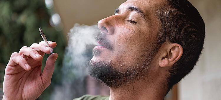 Online-Seminar „Cannabis und Suchtprävention im Unternehmen“: Person raucht einen Joint mit geschlossenen Augen.