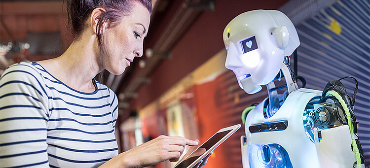 KI und Arbeit: Frau mit Tablet vor einem humanoiden Roboter