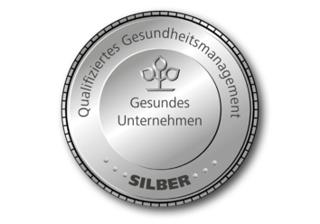 Silberfarbendes, rundes Siegel auf dem „Gesundes Unternehmen, Qualifiziertes Gesundheitsmanagement“ und „Silber“ steht.