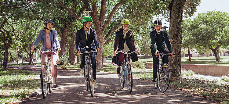 Klimabewusstes Unternehmen: vier Menschen auf dem Fahrrad unterwegs im Grünen