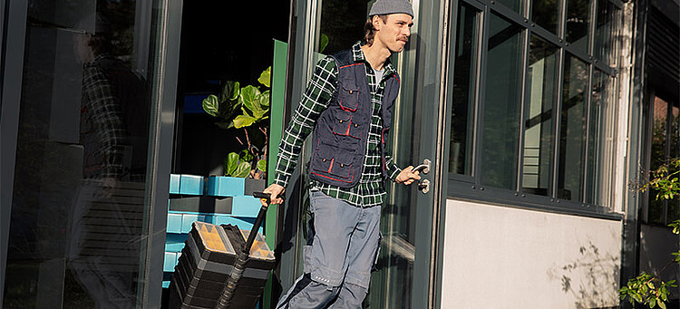 Online-Seminar „Ende von Beschäftigungen“: Mann mit Rollkoffer verlässt ein Gebäude. Online-Seminar „Ende von Beschäftigungen“: Mann mit Rollkoffer verlässt ein Gebäude.