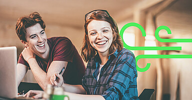 Zwei lächelnde Auszubildende in einer Werkstatt-Umgebung mit eingeblendetem grünen Grafik-Symbol.