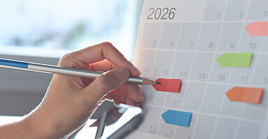 Neues zum Jahreswechsel: Hand markiert mit Bleistift auf Kalenderblatt Januar 2026