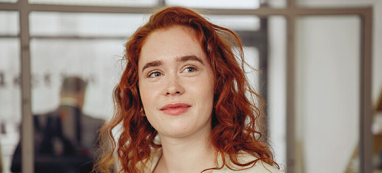 Junge, rothaarige Frau mit optimistisch-freundlichem Blick.