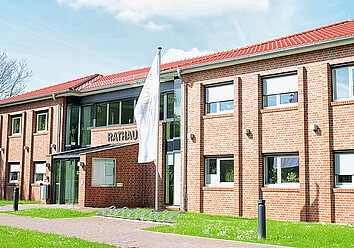 Das Verwaltungsgebäude der Gemeinde Hinte ist einer von acht Standorten, an denen die Mitarbeitenden im Einsatz sind. Backstein-Verwaltungsgebäude der Gemeinde Hinte von außen.