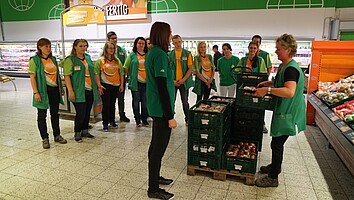 AOK-Sportfachkraft Daniella Keulen leitet an zum rückengerechten Heben von Gemüsekisten