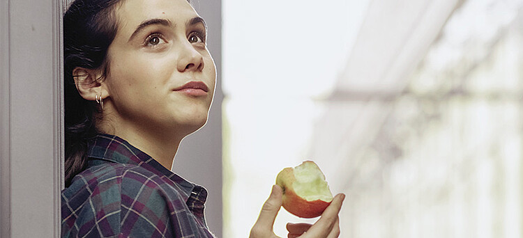 Eine junge Frau beißt in einen Apfel