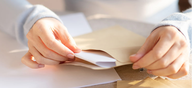 Zentrales Postfach bei der AOK Niedersachsen Frauenhände stecken einen Brief in einen Umschlag