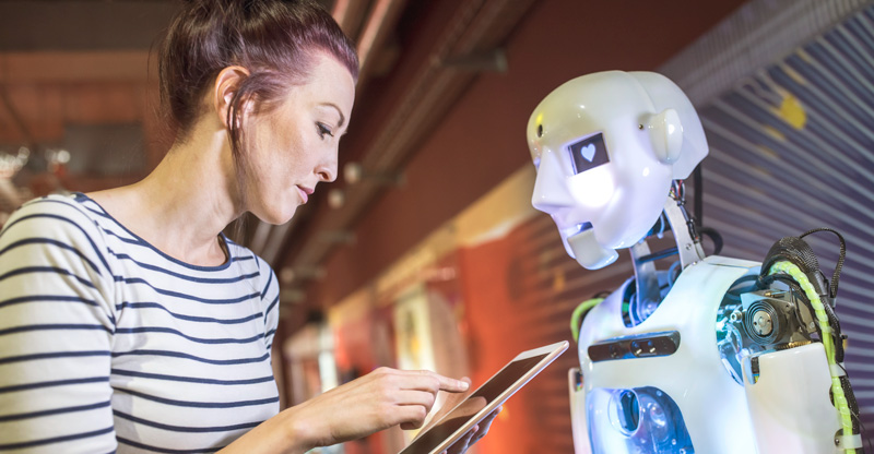 KI und Arbeit: Frau mit Tablet vor einem humanoiden Roboter