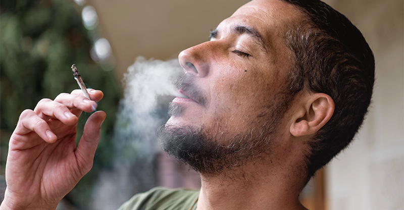 Online-Seminar „Cannabis und Suchtprävention im Unternehmen“: Person raucht einen Joint mit geschlossenen Augen.