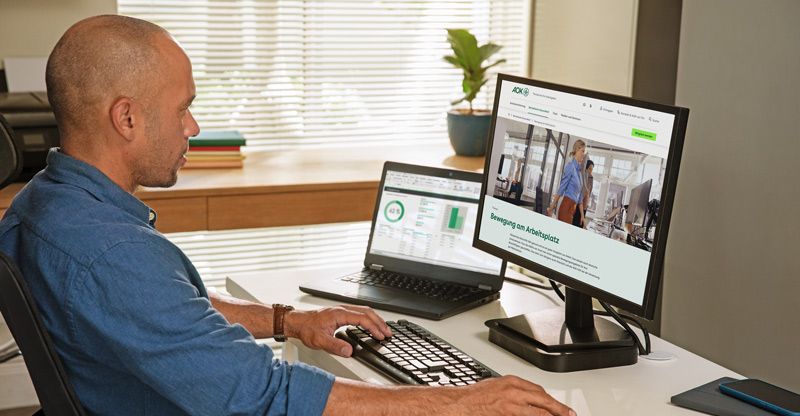 Homeoffice: Mann sitzt am heimischen Schreibtisch mit zwei Bildschirmen