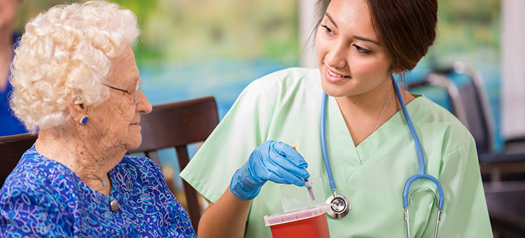 Besser abgesichert in der Ausbildung. Eine Krankenpflege-Auszubildende mit einer älteren Patientin.