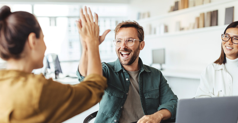Ein Mann und ein Frau geben sich lachend ein „High Five“
