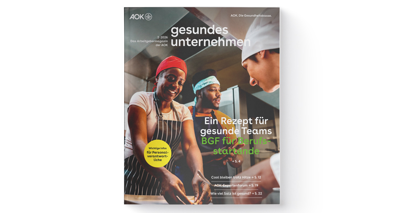 gesundes unternehmen Ausgabe 2-2026: Drei Personen arbeiten zusammen in einer Küche