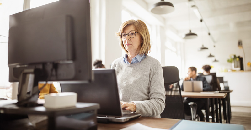 Eine Frau sitzt vor ihrem Monitor in einem Büro.