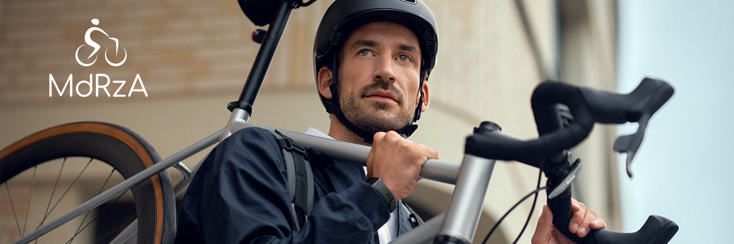 Mann mit Fahrradhelm trägt Fahrrad auf einer Treppe zur Arbeit.