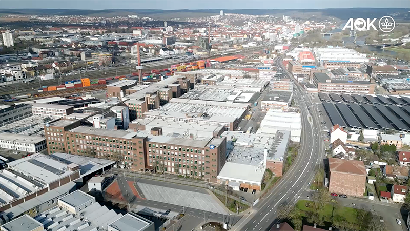 Praxisbeispiel ZF Standort Schweinfurt Praxisbeispiel ZF Standort Schweinfurt: Luftaufnahme des ZF-Werksgeländes in Schweinfurt mit Industriegebäuden, mehrspuriger Hauptstraße und Stadtpanorama im Hintergrund.
