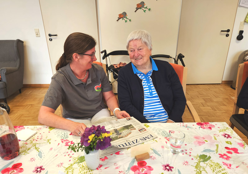 Alltagssituation in der Pflege Pflegefachkraft liest Bewohnerin eine Zeitung vor