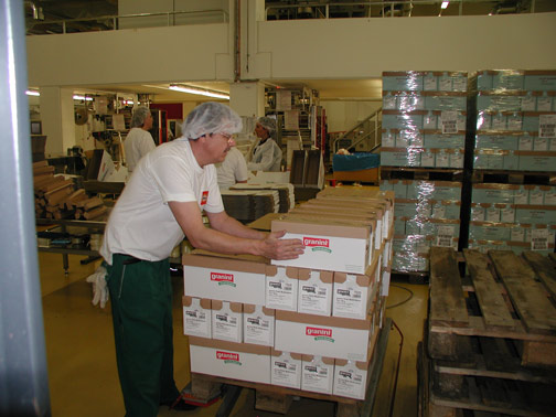 Mitarbeiter in der Produktion stapelt Kartons