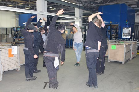 Mitarbeiter bei Bewegungsübungen in der Werkshalle