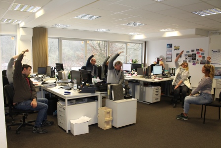 Mitarbeiter machen Bewegungsübungen am Schreibtisch