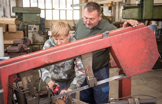 Produktionsmitarbeiter Mitarbeiter schaut jungem Kollegen über die Schulter