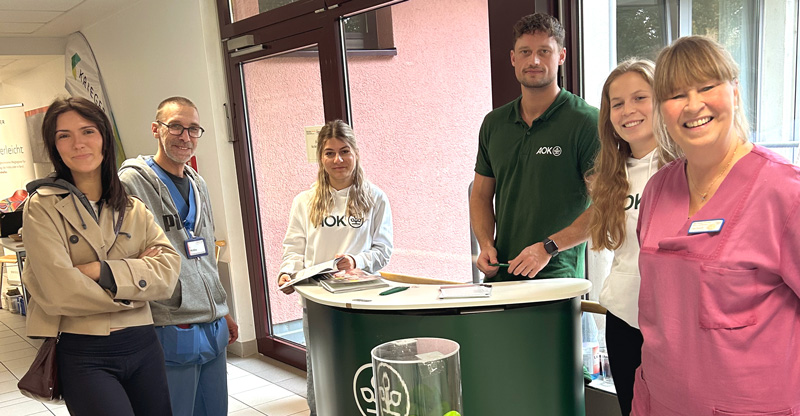 BDH-Klinik Vallendar: Vier Frauen und zwei Männer stehen an einem AOK Pult.