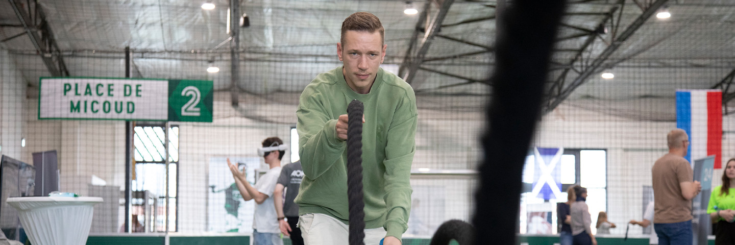 Gesundheitstag im Unternehmen: junger Mann trainiert an einem Seil in einer Sporthalle. Gesundheitstag im Unternehmen: junger Mann trainiert an einem Seil in einer Sporthalle.