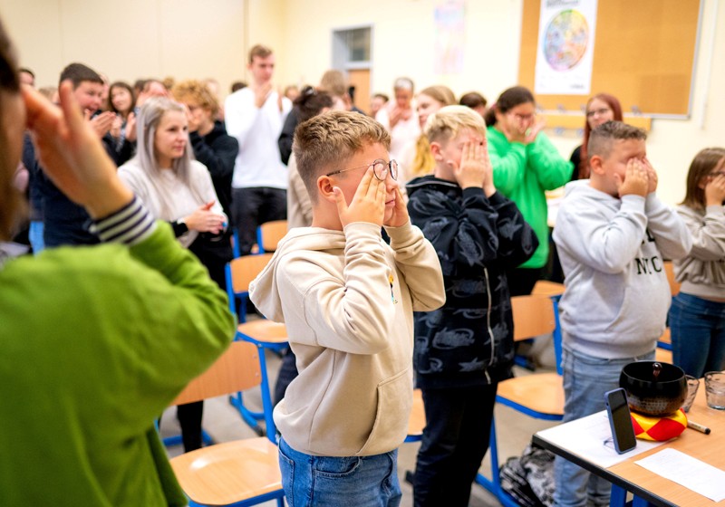 Projekt ABiK der Uni Leipzig: Kinder und Erwachsene befinden sich in einem Klassenzimmer und machen gemeinsam eine Übung, bei der sich die Kinder die Augen zuhalten Projekt ABiK der Uni Leipzig: Kinder und Erwachsene befinden sich in einem Klassenzimmer und machen gemeinsam eine Übung, bei der sich die Kinder die Augen zuhalten