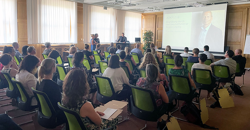 Netzwerktreffen Leipzig: Zuhörer gucken im Konferenzraum auf Beamerleinwand