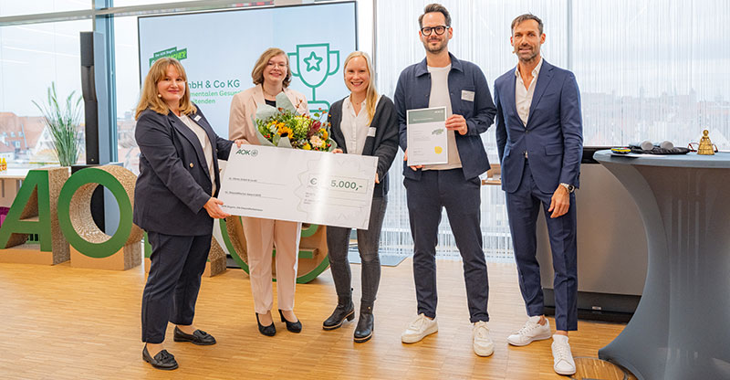 Preisverleihung GesundMacher Award 2025: Eine Gruppe von Personen präsentiert einen Gewinnerscheck Preisverleihung GesundMacher Award 2025: Eine Gruppe von Personen präsentiert einen Gewinnerscheck
