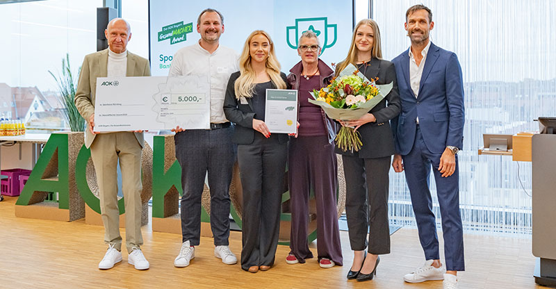 Preisverleihung GesundMacher Award 2025: Eine Gruppe von Personen präsentiert einen Gewinnerscheck Preisverleihung GesundMacher Award 2025: Eine Gruppe von Personen präsentiert einen Gewinnerscheck