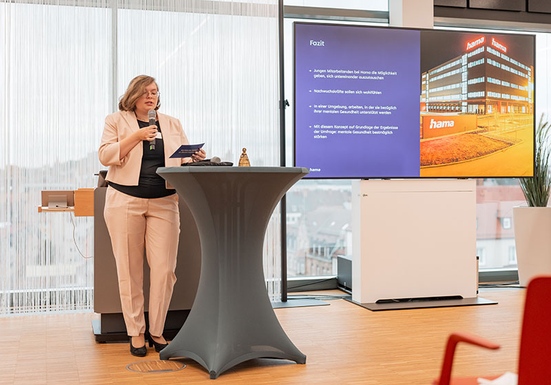 GesundMacher Award 2025: Frau mit Mikrofon hält eine Präsentation GesundMacher Award 2025: Frau mit Mikrofon hält eine Präsentation