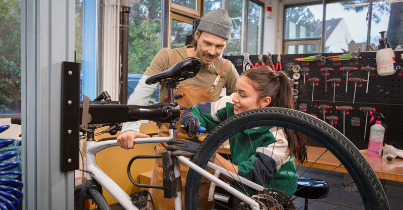 Zwei Kollegen die an einem Fahrrad schrauben.