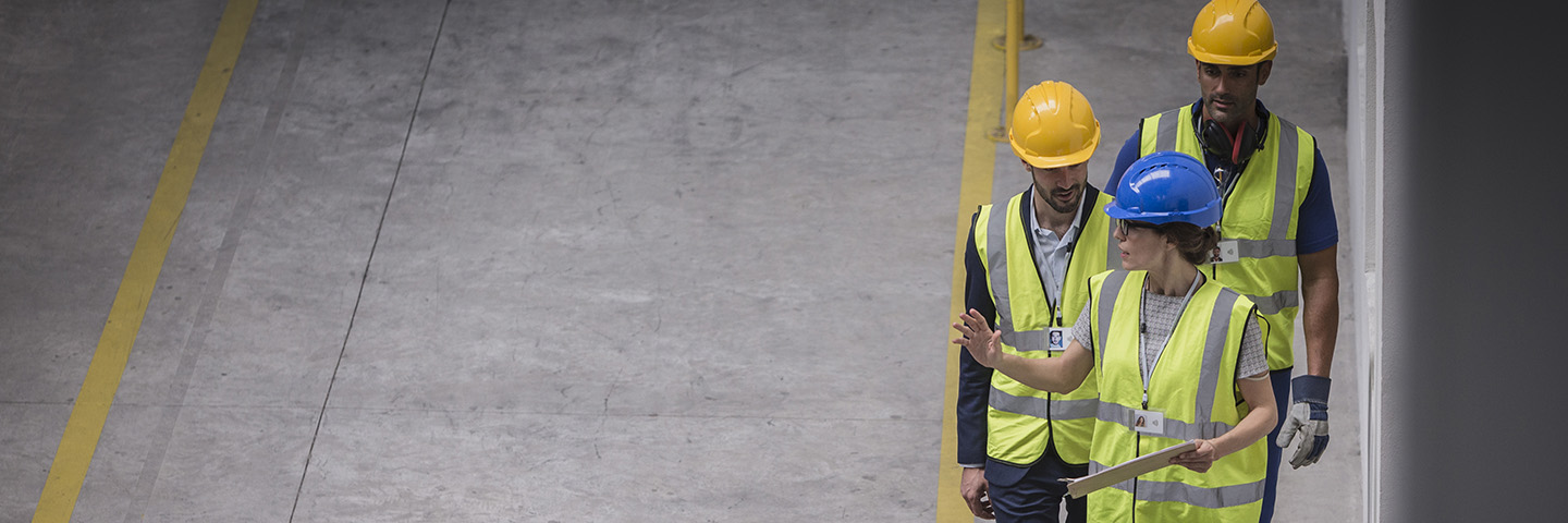 Arbeitgeber sind verpflichtet, sich von Experten für Arbeitssicherheit beraten zu lassen Drei Arbeitnehmer in Sicherheitswesten und Helmen machen eine Sicherheitsinspektion