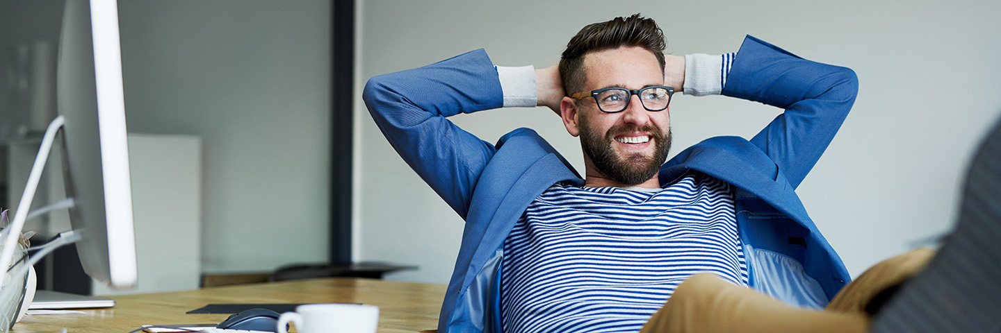 Unser Berufsleben nimmt Einfluss auf unsere psychische Gesundheit Ein glücklicher Mann sitzt in einem Büro