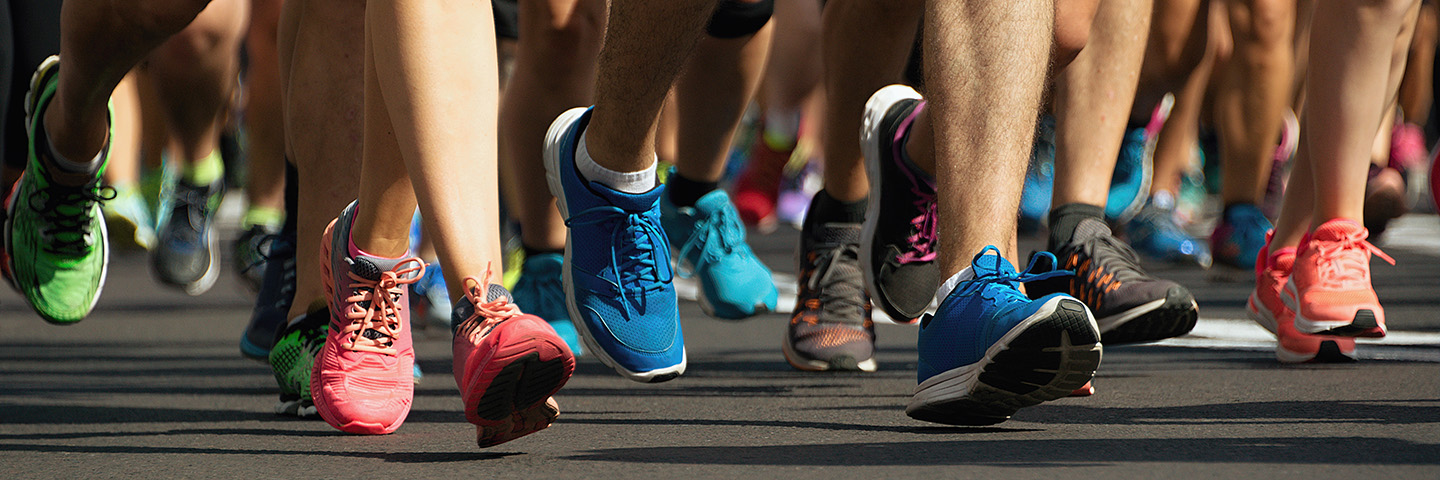 Regelmäßige Bewegung kann viele Krankheiten vorbeugen Viele laufende füßen auf einem Marathon