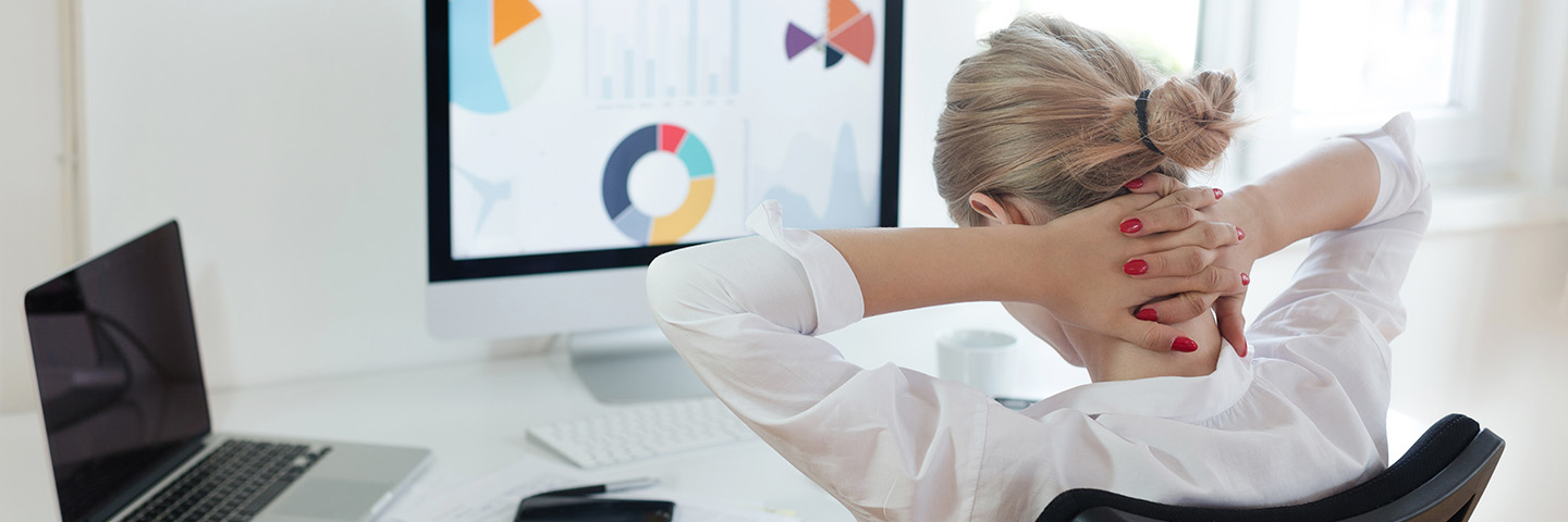 Einseitige Belastungen, Fehlhaltungen sind ein entscheidender Faktor für Rückenschmerzen Eine Frau sitzt vor einem Computer und hält sich ihren verspannten Nacken