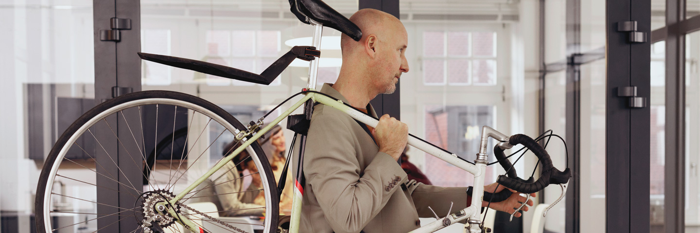 Ein Mann trägt sein Rennrad durchs Büro.