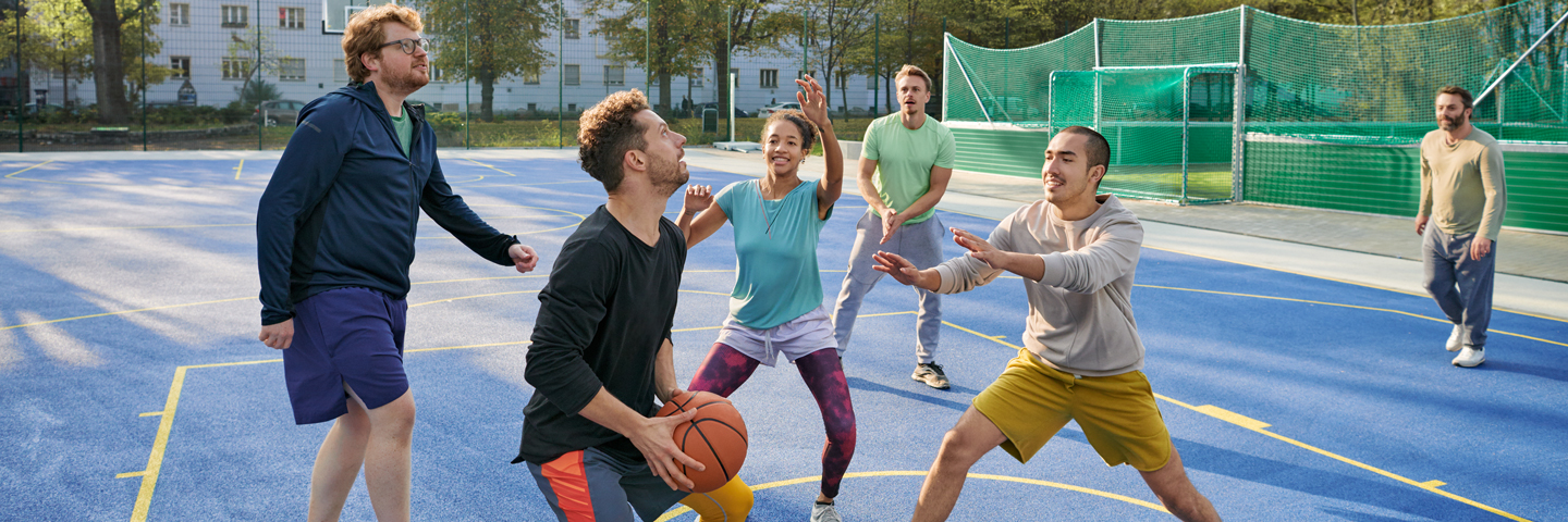 Eine Gruppe von sechs Personen spielt auf einem Basketballplatz zusammen.